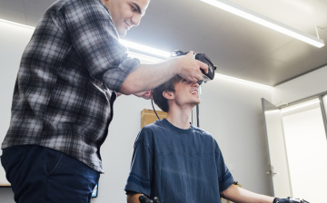 Aryan Zoroufi helping Beckett Roberge put on a VR headset.