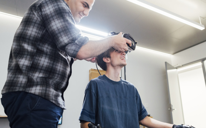 Aryan Zoroufi helping Beckett Roberge put on a VR headset.
